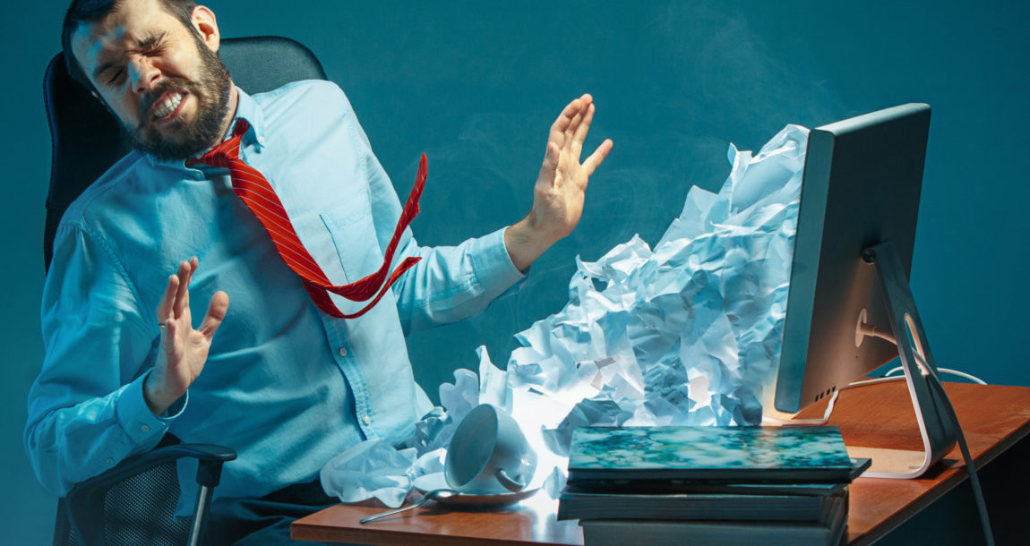 Man sitting at computer being covered in paper emails pouring out of a monitor.