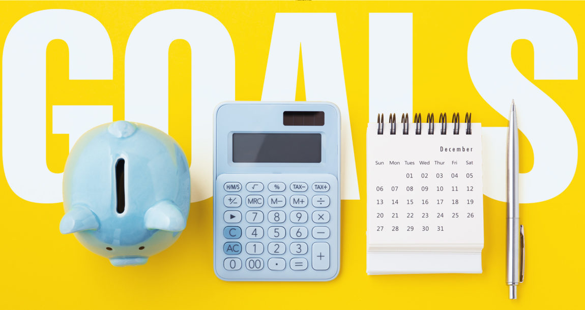 The word "Goals" with a piggy bank, calculator and calendar in front.