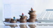 Tiny human figures sitting on stacks of coins