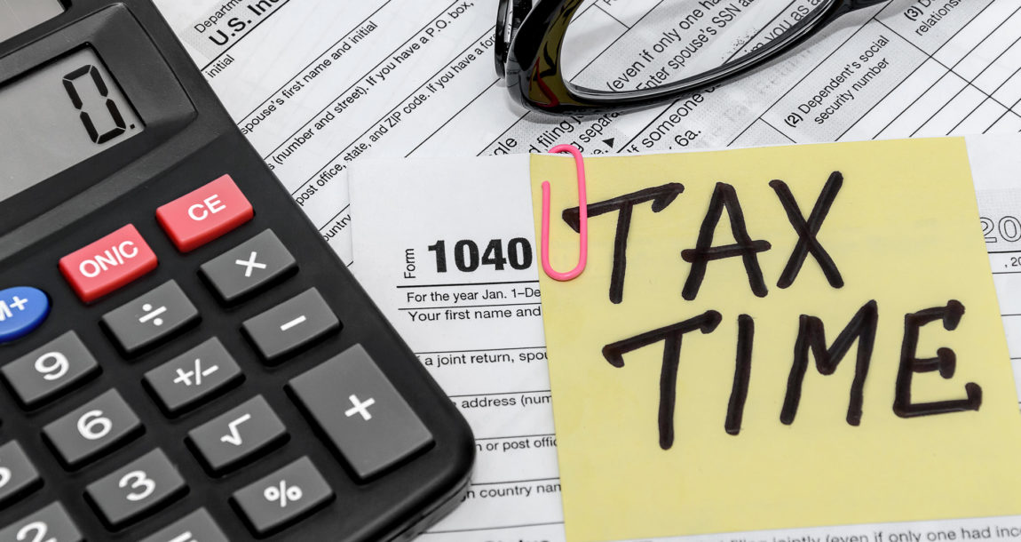 Image of 1040 tax form, calculator and a memo saying, "tax time."