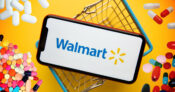 Image of the Walmart logo on a cell phone sitting atop a shopping basket.