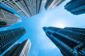 Image looking up into the sky amid a number of skyscrapers. $1.5 trillion debt signals trouble for commercial real estate market.