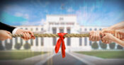 Image of two people having a tug of war in front of the Federal Reserve building. The Fed continues its tug-of-war with inflation, raises rates again.