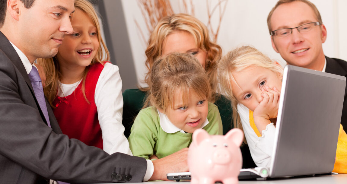 Image of a large family gathered around a desk with a financial advisor, with a piggy bank sitting on the desk. Inheritors likely to keep family advisor if relationship established early.