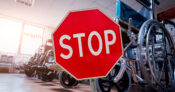 Stop sign positioned in front of a row of wheelchairs. Despite need, many advisors don’t recommend LTC protection to clients.