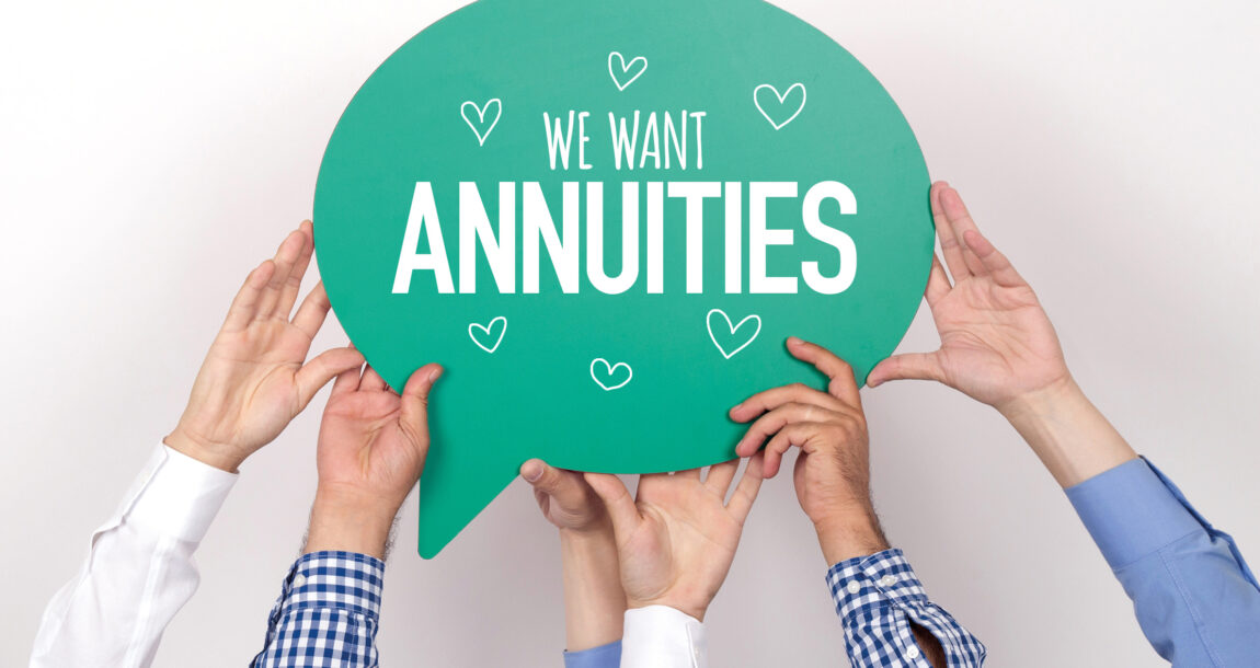 Image of many pairs of hands holding up a sign that says "We want annuities." Interest grows in annuities as part of employer-sponsored retirement plans.