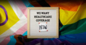 Image shows a sign asking for healthcare coverage against a transgender pride backdrop.