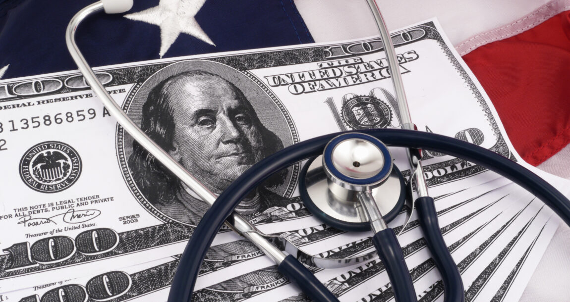 Image of hundred dollar bills and a stethoscope against a background of the American flag.