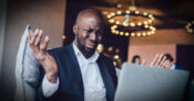 Man dressed in business attire, staring at his laptop screen looking perplexed.