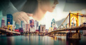 Image shows the Pittsburgh skyline with a woman in the background.