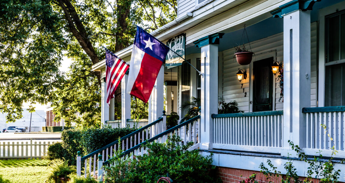 Image shows a home with the Texas flag and the United States' flag.