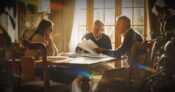 Image of a financial advisor sitting at a table with a couple of clients. How-to-leverage-your-client-base-to-grow-your-practice.