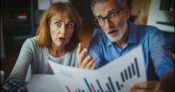 Image shows a bewildered couple looking at a financial statement.