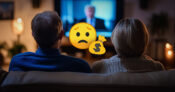 Image of a couple watching TV show featuring a political candidate with an overlay of a cartoon character with a sad face holding a bag of money. Most-Americans-fear-financial-decline-if-their-preferred-candidate-loses.