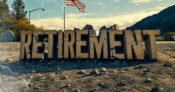 Photo illustration of showing the word "Retirement" made of cracked rock, sitting on a landscape scattered with debris, and with an American flag in the background. Is-the-American-retirement-system-broken.