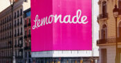 Image of a business district with a large "Lemonade" sign wrapping around a corner building. Has-insurtech-Lemonade-finally-turned-the-corner.