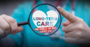 The words "Long-term Care" seen through a magnifying glass. As-LTC-hits-a-crisis,-a-call-to-reach-middle-income-Americans.