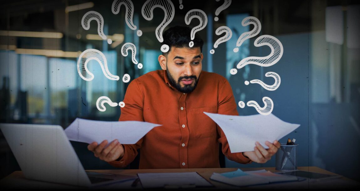 Image shows a man with pieces of paper in both hands and question marks above his head.