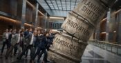Image shows a group of people knocking over a column.