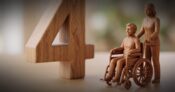 Image shows a number 4 and a wooden man in a wheelchair
