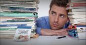 Image shows a man looking at a stack of forms.