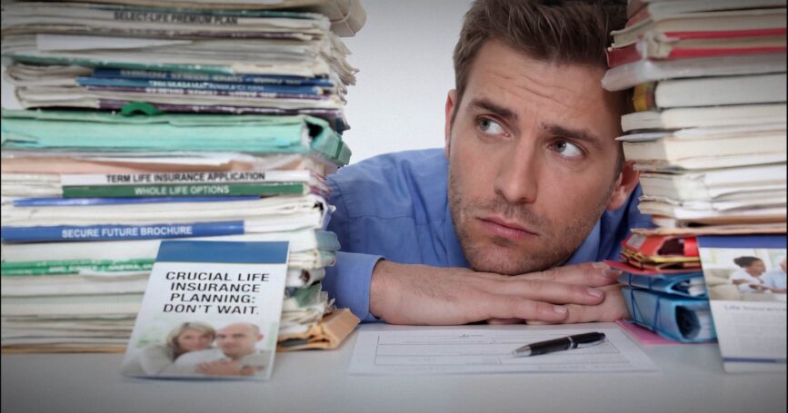 Image shows a man looking at a stack of forms.
